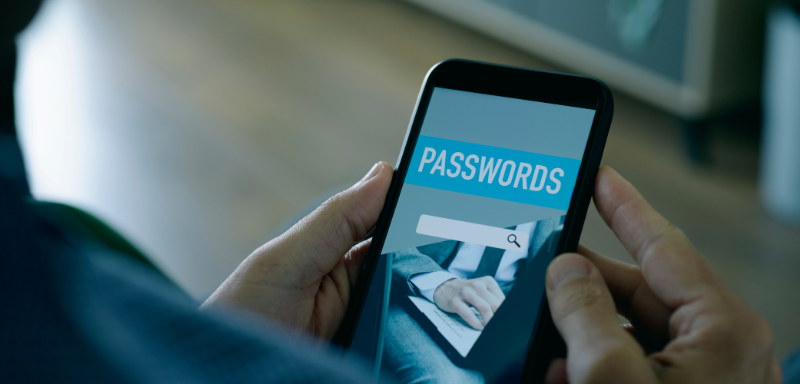 A man holds a cell phone with "passwords" written on the screen.